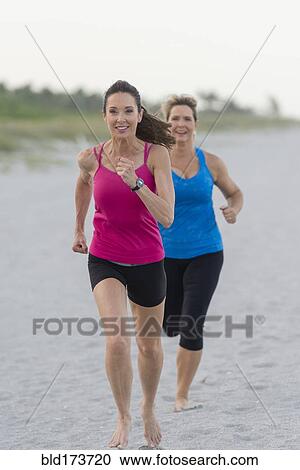 Stock Image - Caucasian women running on beach. Fotosearch