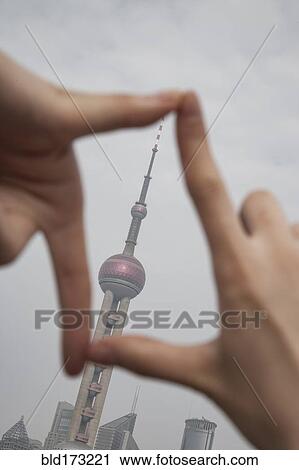 Stock Image - Chinese woman framing Shanghai tower, Shanghai, China. Fotosearch