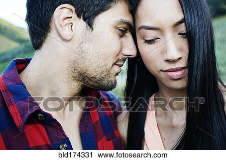 Stock Image - Close up of couple nuzzling outdoors. Fotosearch