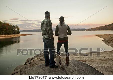 Stock Photo - Couple and dog admiring remote lake. Fotosearch