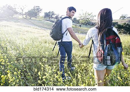 Picture - Couple carrying backpacks in field. Fotosearch