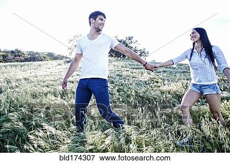 Stock Photo - Couple holding hands in field. Fotosearch