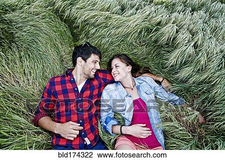 Stock Image - Couple laying in grass. Fotosearch