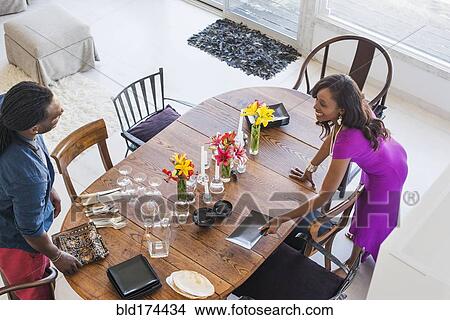 Picture - Couple setting dining room table. Fotosearch