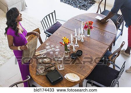 Stock Image - Couple setting dining room table. Fotosearch
