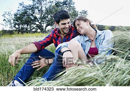 Stock Image - Couple sitting in field. Fotosearch
