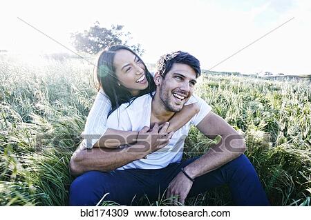 Couple sitting in field View Large Photo Image Stock Photo - Couple sitting in field. Fotosearch