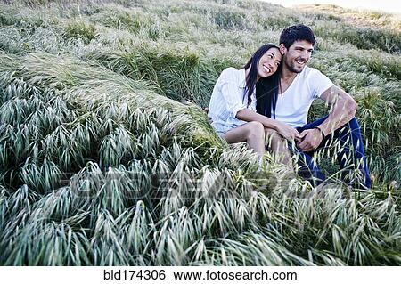 Stock Photograph - Couple sitting in grass. Fotosearch