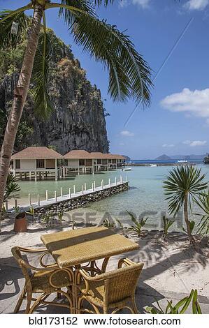 Stock Image - Dock and huts on tropical beach. Fotosearch