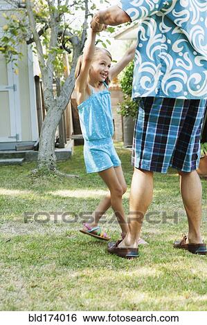 Stock Photograph - Father and daughter dancing in backyard. Fotosearch