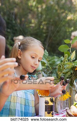 Stock Photography - Girl picking flowers and berries in backyard. Fotosearch