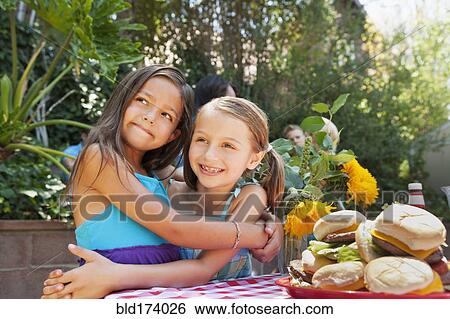 Girls hugging at backyard barbecue View Large Photo Image Stock Photograph - Girls hugging at backyard barbecue. Fotosearch