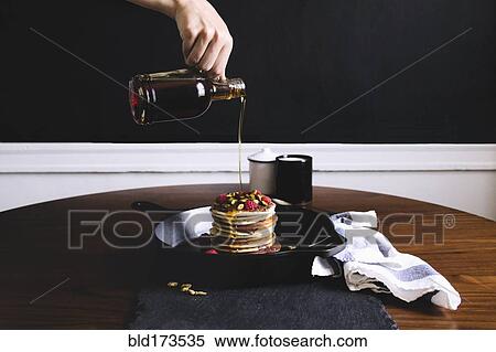 Hand pouring syrup on pancakes View Large Photo Image Stock Photography - Hand pouring syrup on pancakes. Fotosearch
