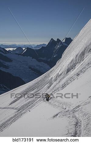 Stock Image - Hiker on snowy mountain slopes. Fotosearch