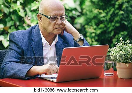 Stock Photograph - Hispanic businessman using laptop outdoors. Fotosearch