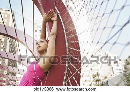 Stock Photograph - Hispanic woman listening to headphones under structure. Fotosearch