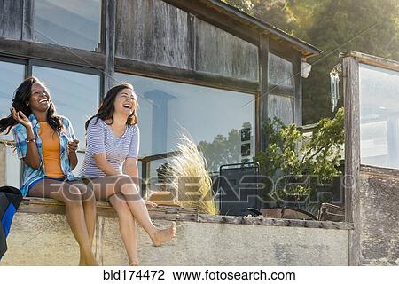 Stock Image - Laughing women sitting in backyard. Fotosearch