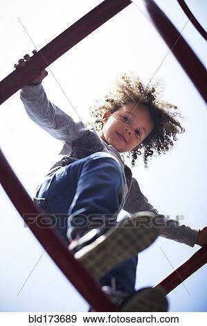 Stock Photo - Low angle view of mixed race boy climbing on play structure. Fotosearch