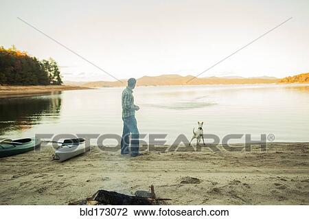 Stock Image - Man and dog playing in remote lake. Fotosearch
