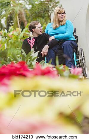 Stock Photo - Man and paraplegic girlfriend exploring garden. Fotosearch