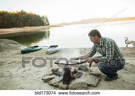 Man building campfire at lake View Large Photo Image Picture - Man building campfire at lake. Fotosearch