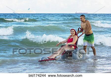 Man pushing paraplegic girlfriend in wheelchair on beach View Large Photo Image Picture - Man pushing paraplegic girlfriend in wheelchair on beach. Fotosearch