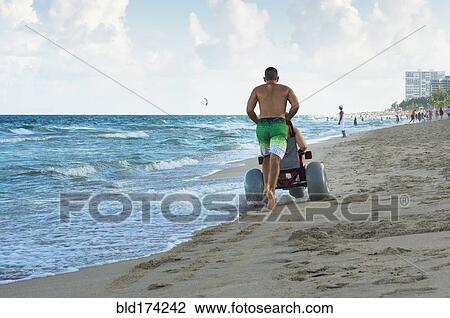 Man pushing paraplegic girlfriend in wheelchair on beach View Large Photo Image Stock Image - Man pushing paraplegic girlfriend in wheelchair on beach. Fotosearch