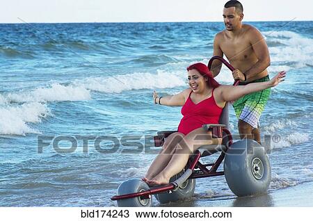 Man pushing paraplegic girlfriend in wheelchair on beach View Large Photo Image Stock Image - Man pushing paraplegic girlfriend in wheelchair on beach. Fotosearch