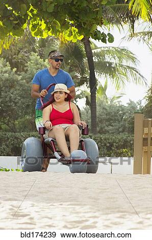 Stock Photo - Man pushing paraplegic girlfriend in wheelchair. Fotosearch