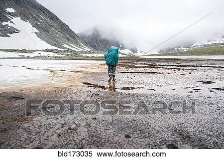 Stock Photography - Mari backpacker walking in remote field. Fotosearch
