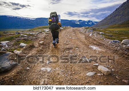 Stock Photo - Mari backpacker walking on dirt path. Fotosearch