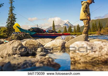Stock Photo - Mari hiker standing on rocks in remote river. Fotosearch
