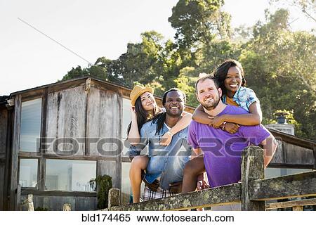 Stock Photography - Men carrying girlfriends piggyback outdoors. Fotosearch