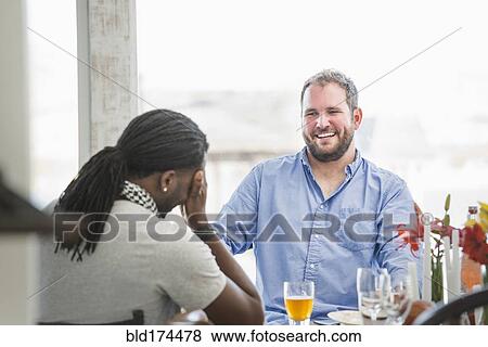 Stock Photo - Men laughing at dinner table. Fotosearch