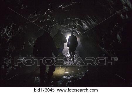 Stock Photography - Men walking in dark cave. Fotosearch