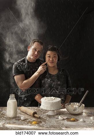Stock Photo - Messy couple baking cake. Fotosearch