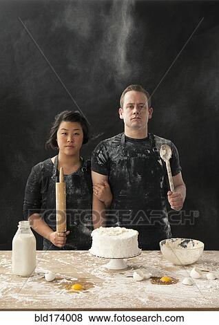 Stock Photo - Messy couple baking cake. Fotosearch