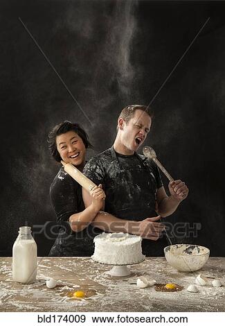 Stock Photo - Messy couple baking cake. Fotosearch