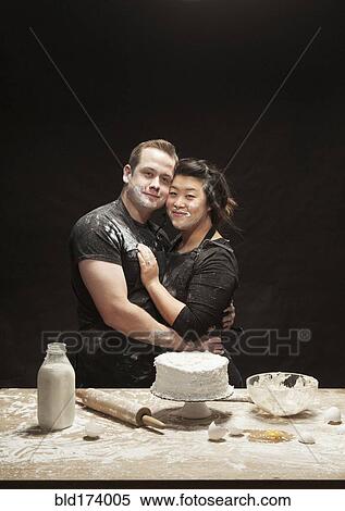 Stock Photography - Messy couple baking cake. Fotosearch
