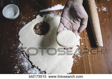 Stock Photography - Mixed race baker cutting circle of dough. Fotosearch
