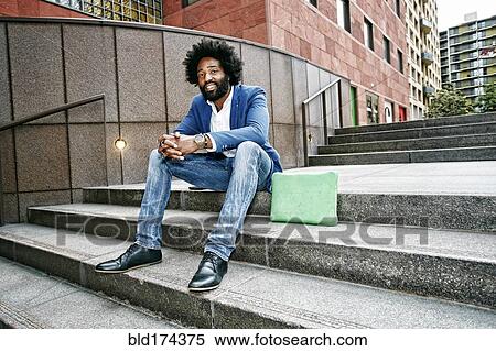 Stock Photography - Mixed race businessman sitting on steps. Fotosearch