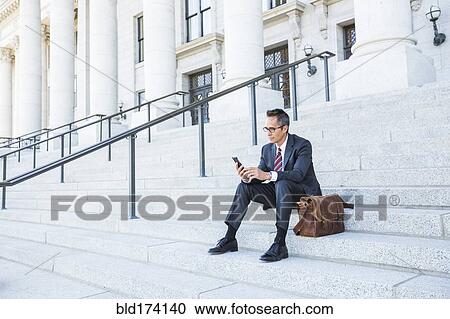 Mixed race businessman using cell phone on courthouse steps View Large Photo Image Stock Image - Mixed race businessman using cell phone on courthouse steps. Fotosearch