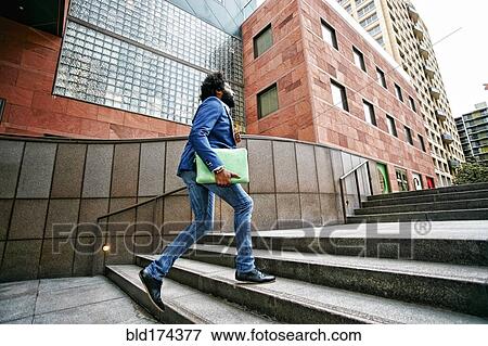 Stock Photo - Mixed race businessman walking on steps. Fotosearch