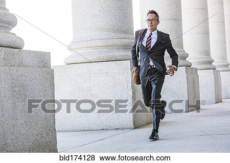 Mixed race businessman walking under columns View Large Photo Image Stock Photo - Mixed race businessman walking under columns. Fotosearch
