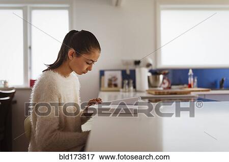 Mixed race girl reading book in kitchen View Large Photo Image Stock Photo - Mixed race girl reading book in kitchen. Fotosearch