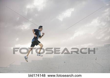 Stock Photo - Mixed race man jogging on steps. Fotosearch