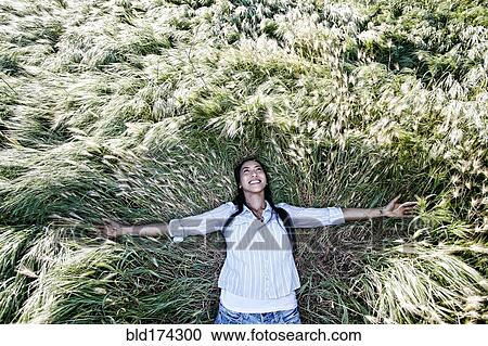 Stock Image - Mixed race woman laying in grass. Fotosearch