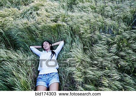 Stock Image - Mixed race woman laying in grass. Fotosearch