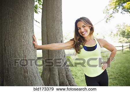 Stock Photo - Mixed race woman leaning on tree. Fotosearch