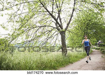 Stock Image - Mixed race woman running on path. Fotosearch